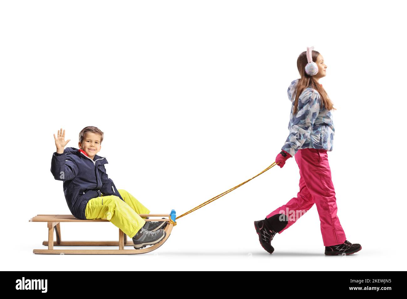 Full length profile shot of a girl pulling a boy on a wooden sled isolated on white background Stock Photo