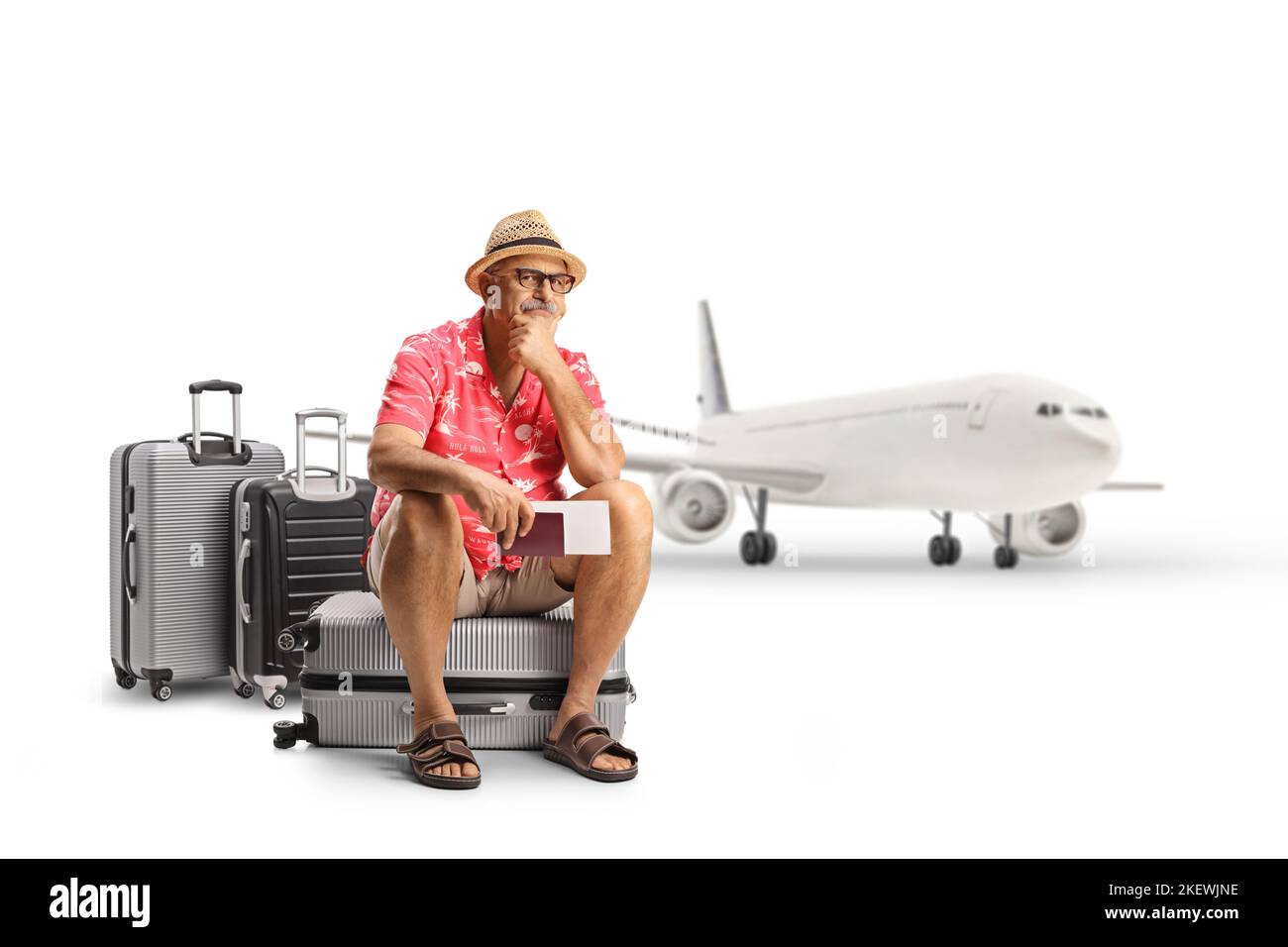 Mature male tourist sitting on a suitcase and waiting in front of an airplane isolated on white background Stock Photo