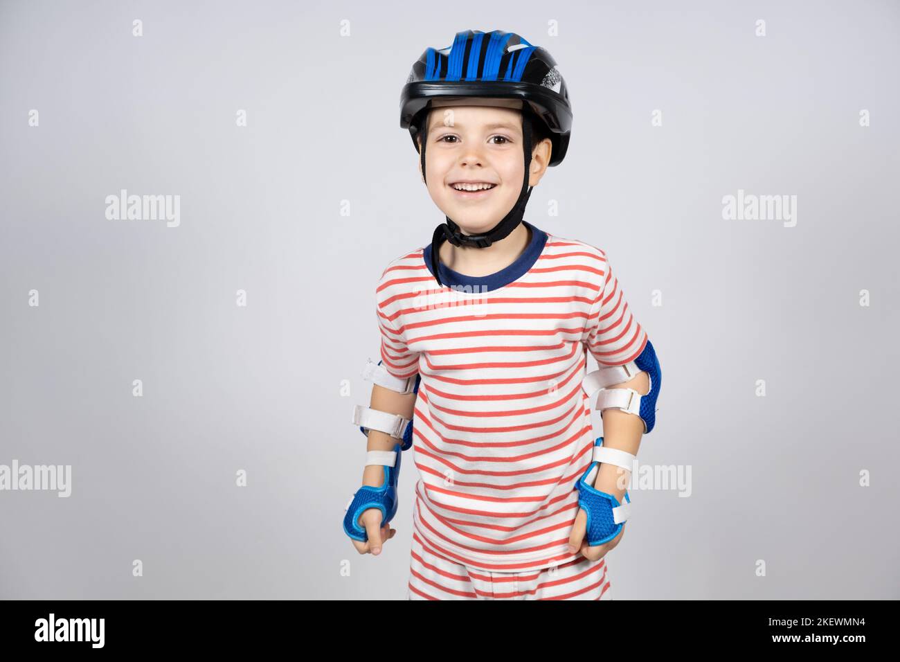 A happy 5yearold boy in a protective helmet, elbow pads and gloves