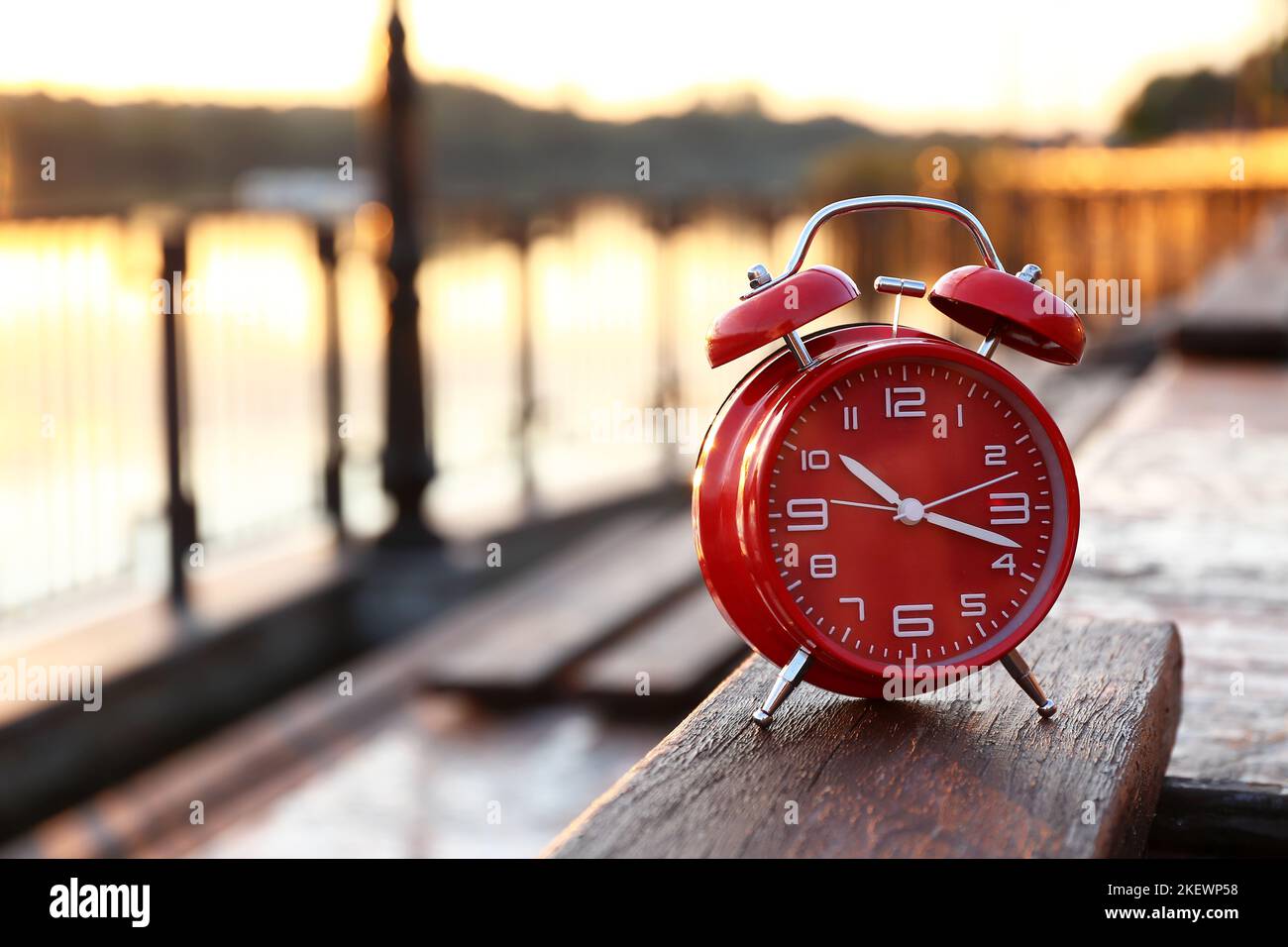 Red vintage alarm clock on embankment at sunrise, closeup Stock Photo ...