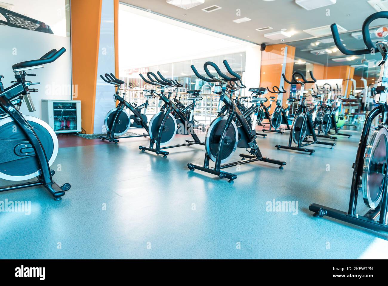Modern gym interior with equipment. Row of training exercise bikes detail, backlight. Healthy lifestyle concept Stock Photo