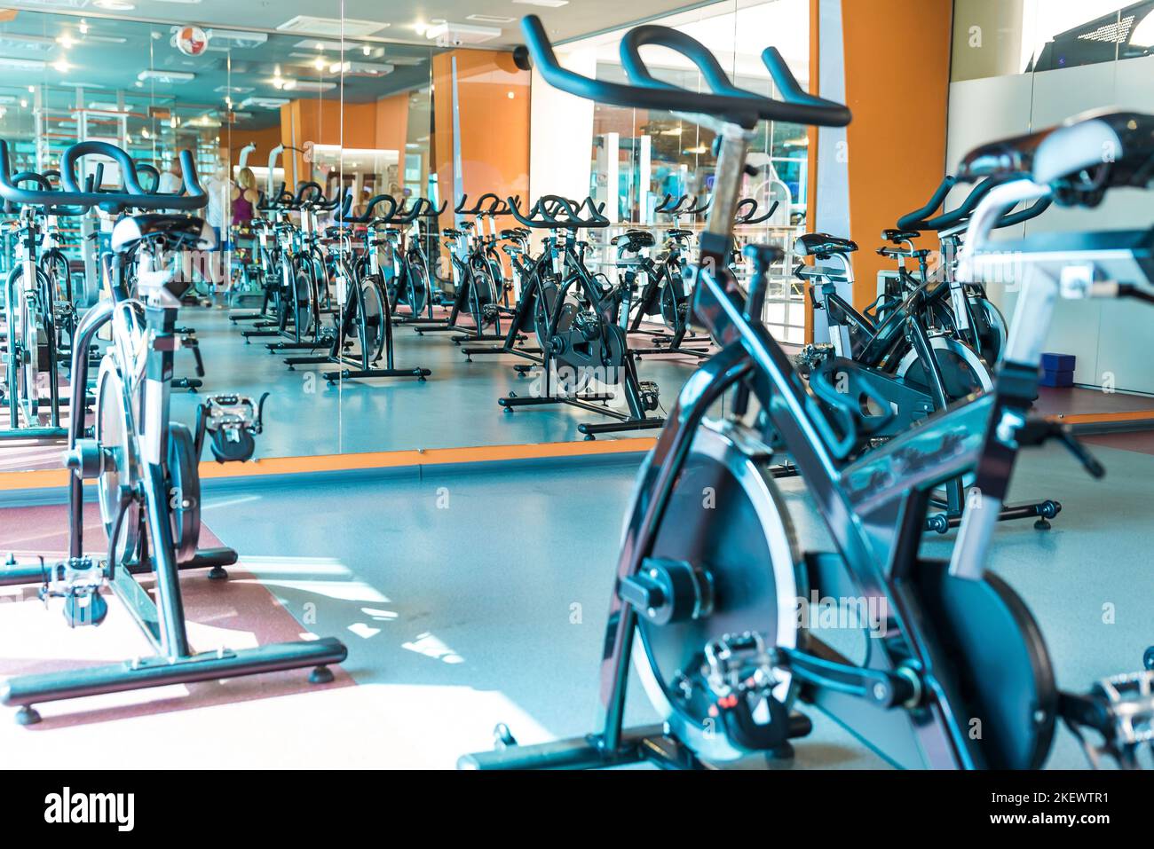 Modern gym interior with equipment. Row of training exercise bikes detail, backlight. Healthy lifestyle concept Stock Photo