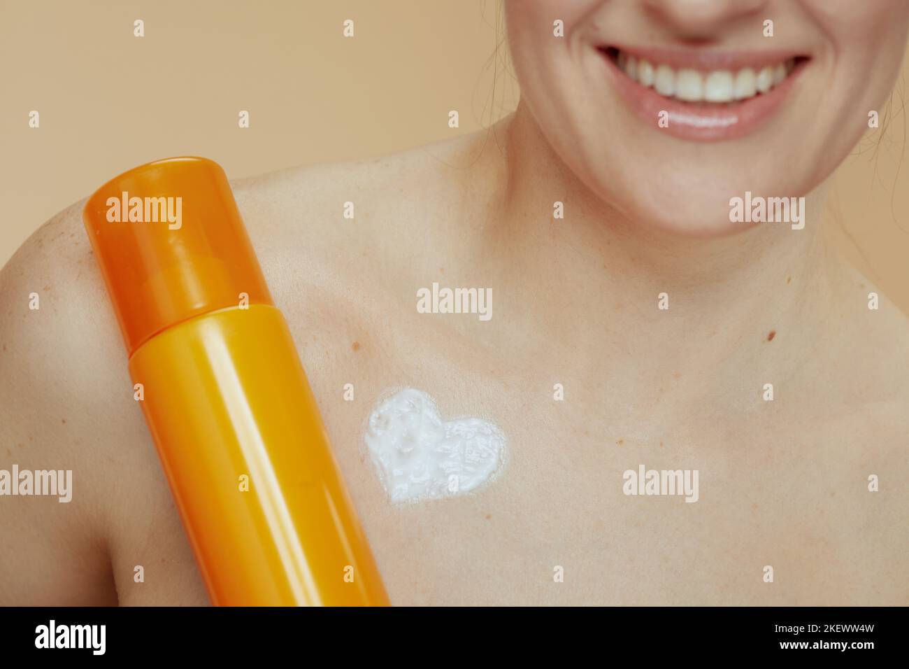 Closeup on young woman with cosmetic cream jar and heart shaped cream on chest. Stock Photo