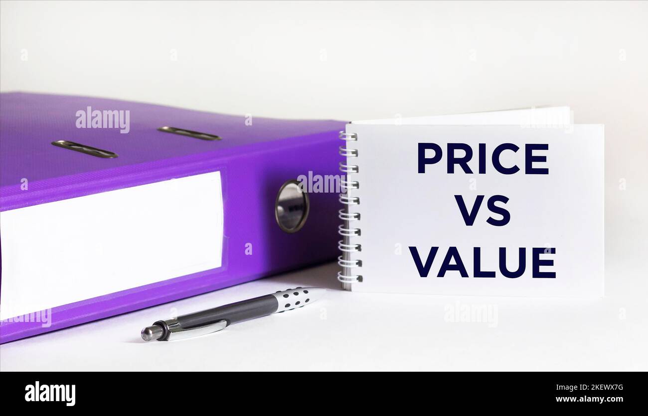 Text price versus cost written on a notepad, next to a folder with documents and a pen on a white background Stock Photo