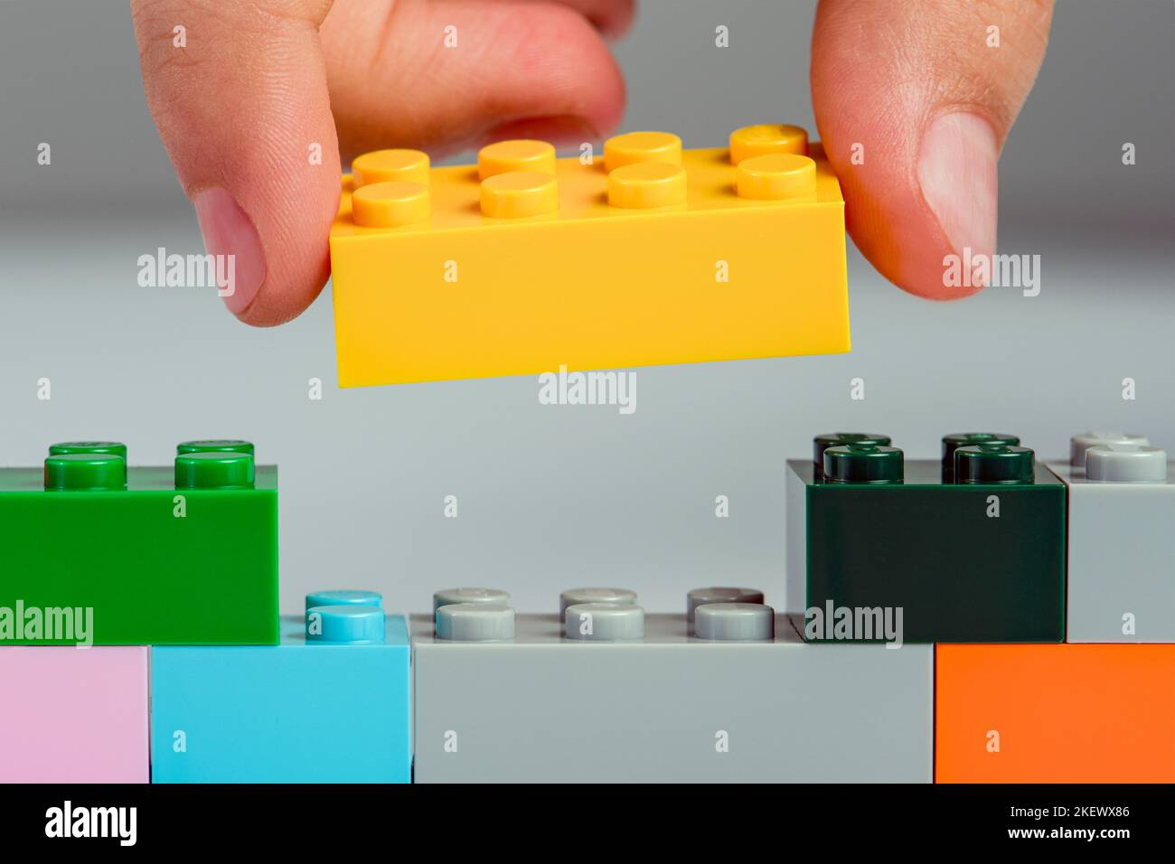 The child builds a tower of blocks. Toy building block in hand close-up. The concept of building and developing fine motor skills of hands Stock Photo