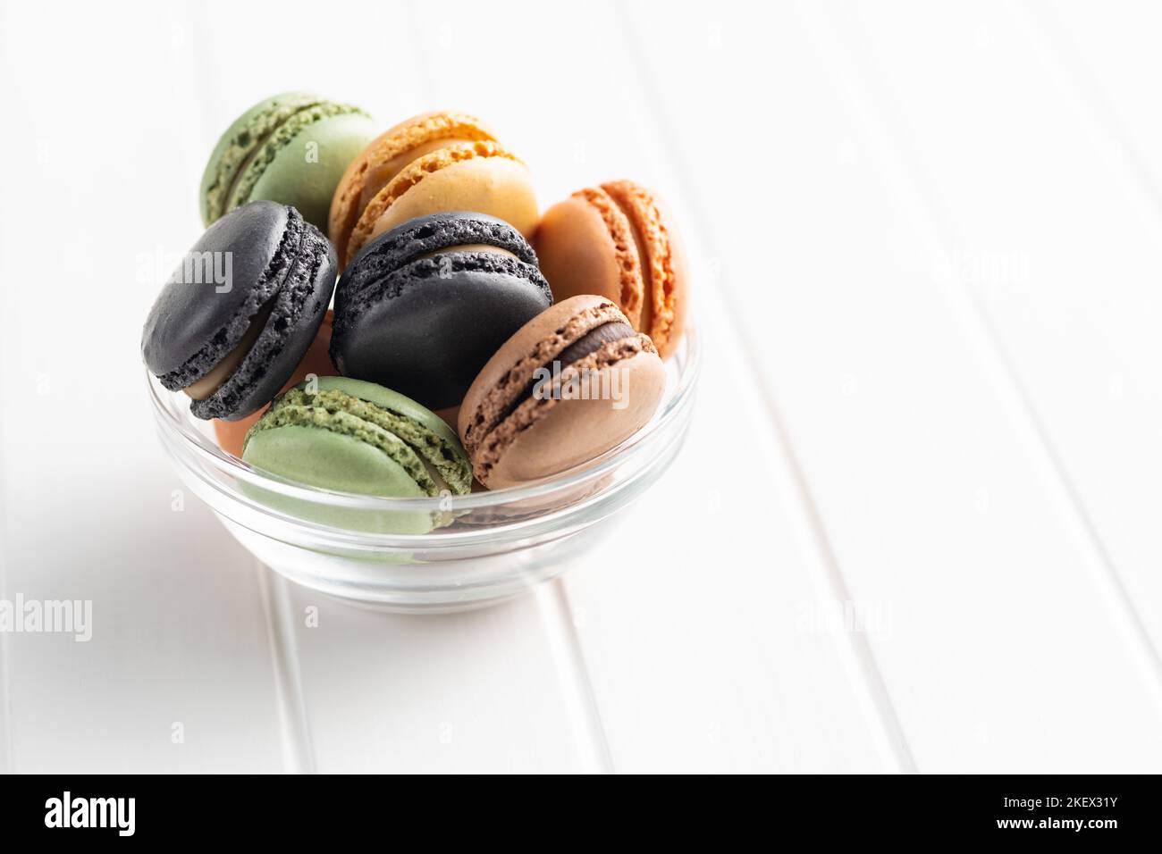 Sweet macaron dessert. Colorful macarons in bowl on the white table. Stock Photo