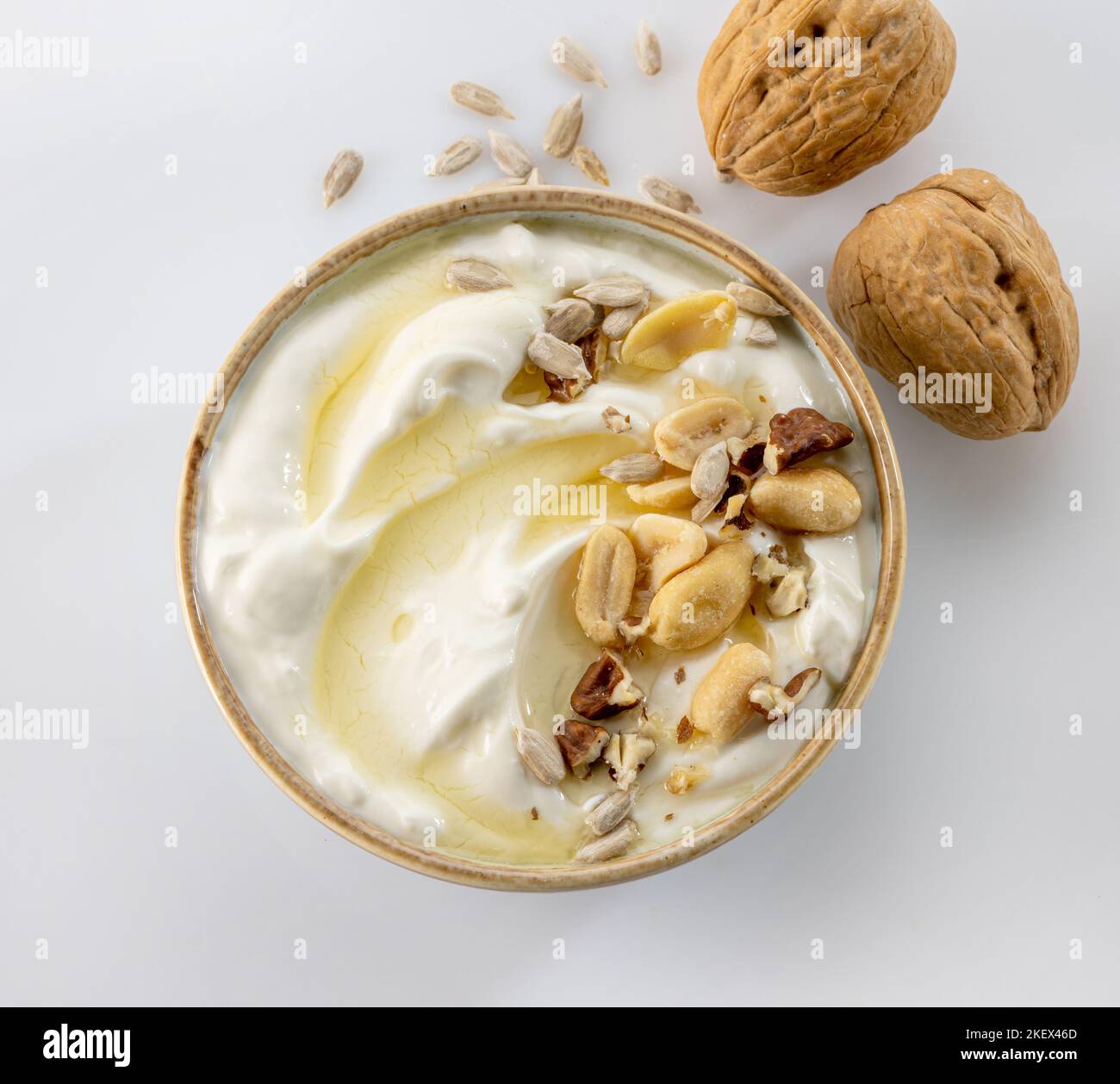 bowl of greek yogurt with honey syrup and nuts on white background, top