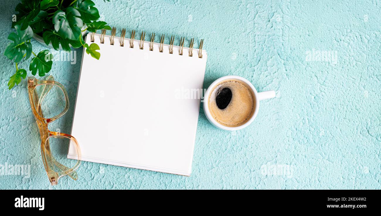 Flat lay of blank notepad on office desk table or workplace with coffee cup, eyeglasses, office supplies with copy space, top view Stock Photo