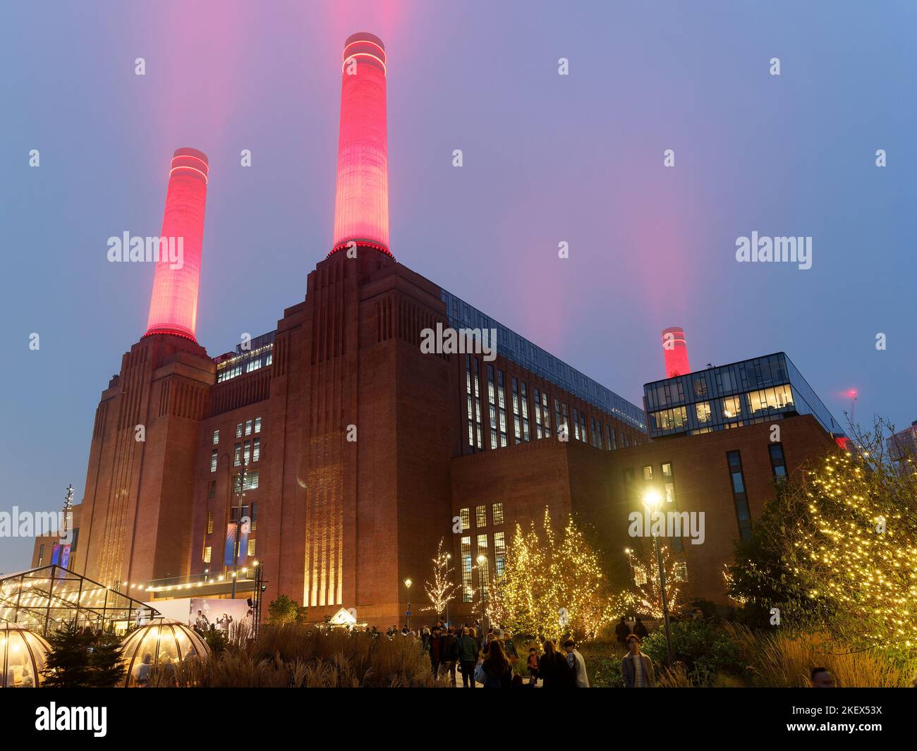 View looking up at Battersea Power Station in London illuminated at night with bright red chimneys piercing the sky Stock Photo