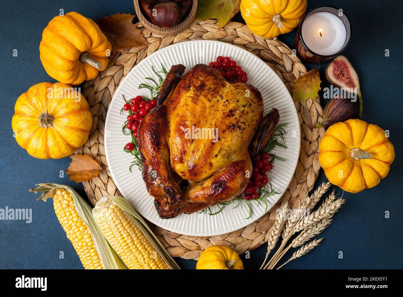 Roasted chicken for Thanksgiving Day. Cooked chicken or turkey with herb rosemary and berry and pumpkins for Thanksgiving dinner on dark table. Festiv Stock Photo