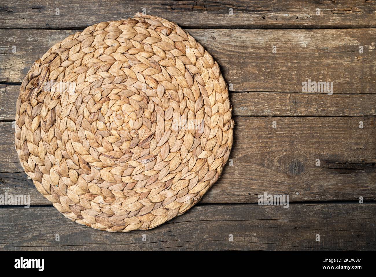 Wicker straw place mat on wooden dark background. Round woven straw mat on wooden gray dining table. Menu, dining, eating concept. Top view, copy spac Stock Photo