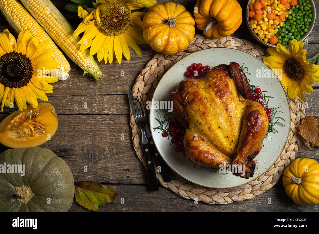 Happy Thanksgiving holiday background. Roasted whole chicken or turkey with autumn vegetables for thanksgiving dinner on wooden background Stock Photo