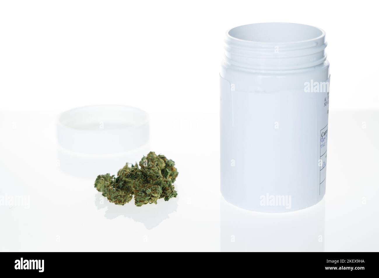 Cannabis flos, medical marijuana next to container on white background Stock Photo