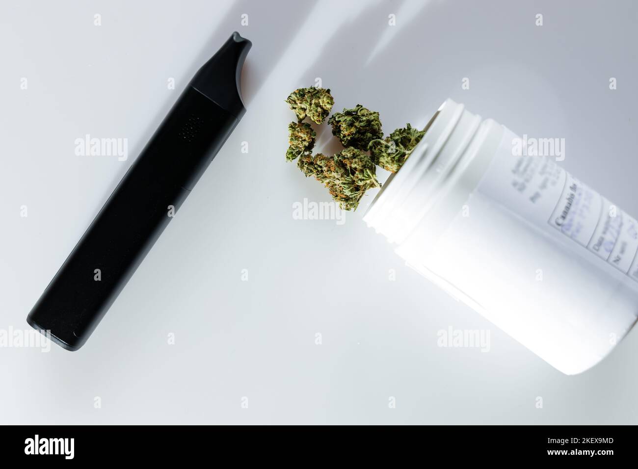 Cannabis flos, medical marijuana in white container next to vaporizer, safe way to take medicine Stock Photo