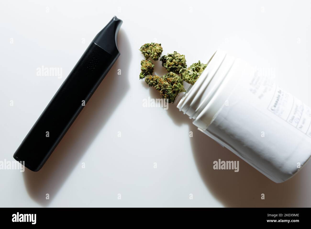 Cannabis flos, medical marijuana in white container next to vaporizer, safe way to take medicine Stock Photo