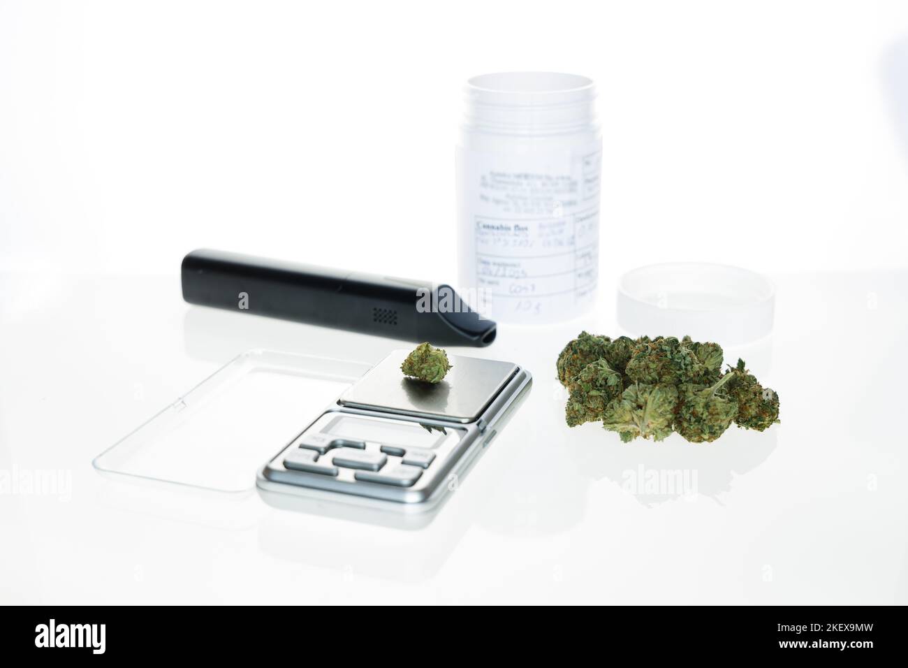 Cannabis flos, medical marijuana pile next to precision scale, vaporizer and white container, safe way to take medicine Stock Photo