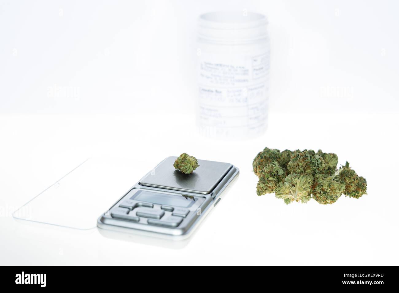 Cannabis flos, medical marijuana pile next to precision scale and white container, safe way to take medicine Stock Photo