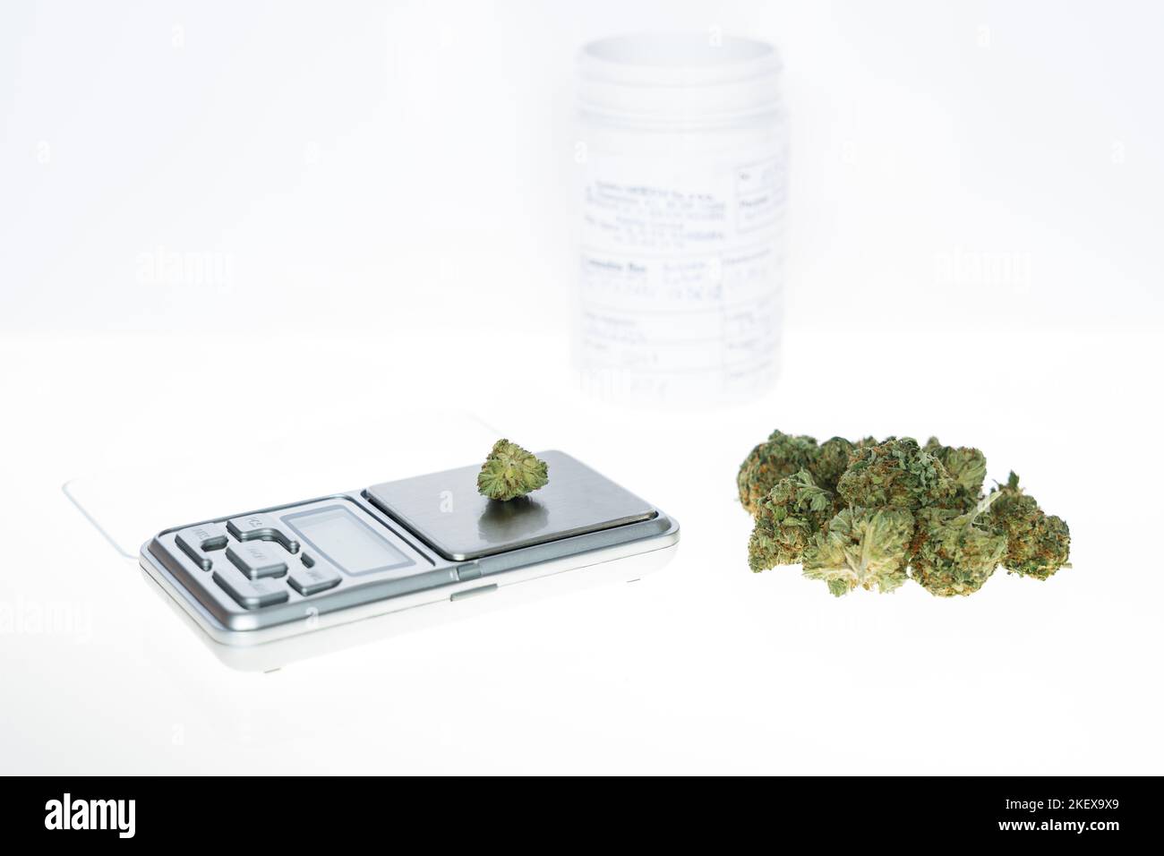 Cannabis flos, medical marijuana pile next to precision scale and white container, safe way to take medicine Stock Photo
