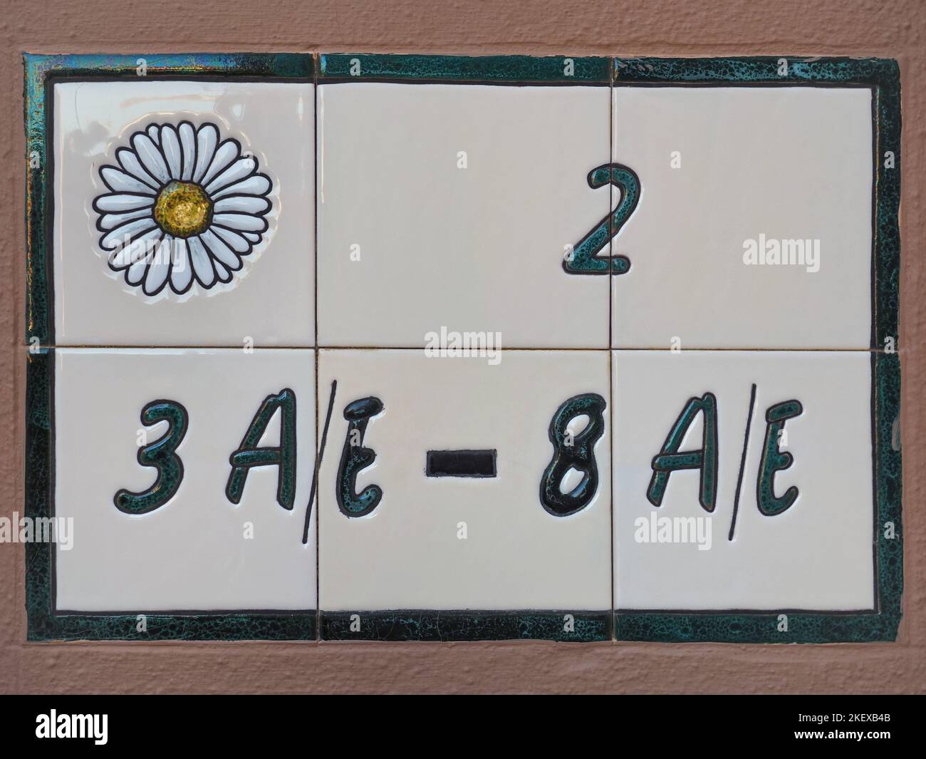 Plate with house or apartment numbers and letters.Traditional Spanish concrete sign of colorful ceramic tiles. Background from painted Azulejos. Stock Photo