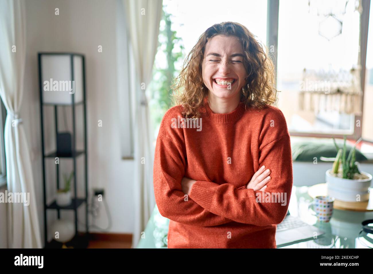 Young funny cheerful pretty lady standing at home and laughing. Stock Photo