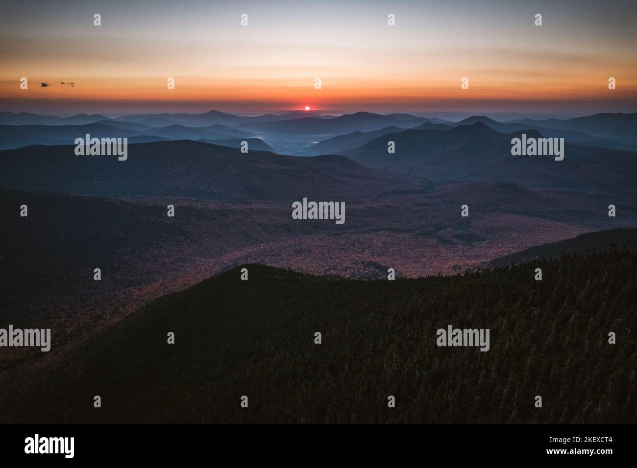 Sun rises over horizon with vibrant fall colors, New Hampshire Stock Photo