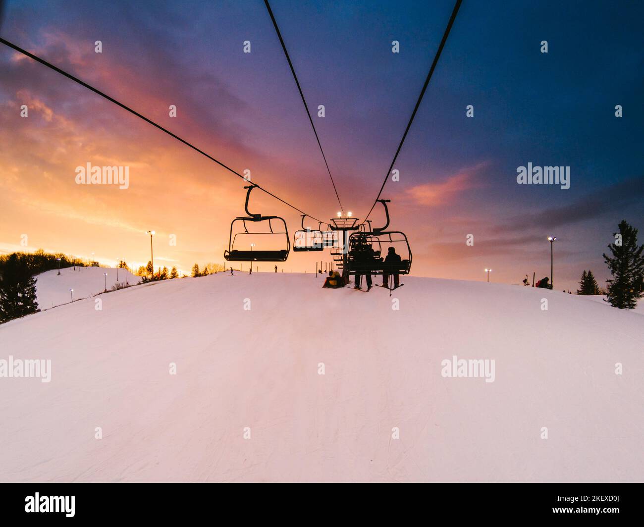 Gorgeous colorful sunset while skiers ride lift to top of mountain ...