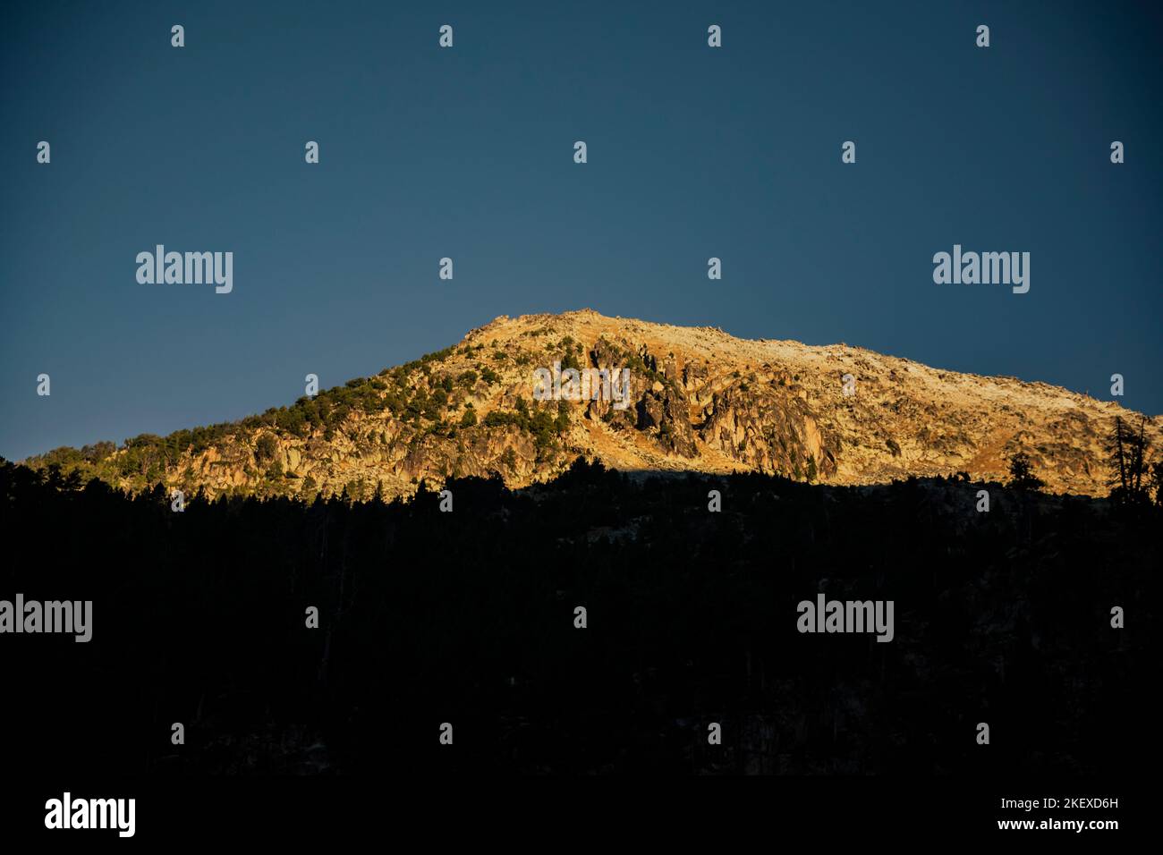 Top of a mountain illuminated by the rays of the sun when it rises Stock Photo