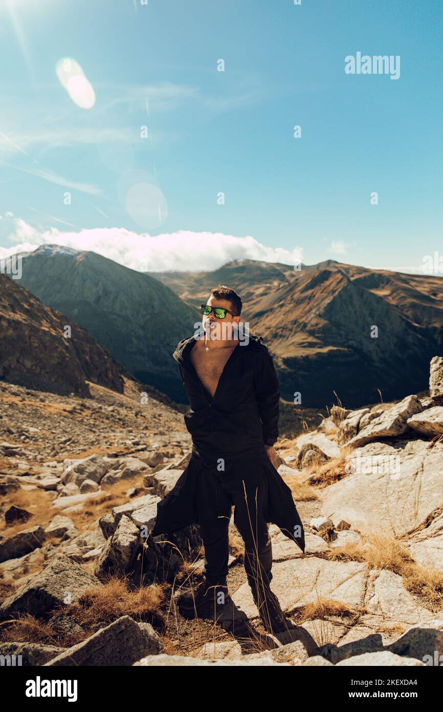 Boy taking off his jacket while climbing a mountain path Stock Photo