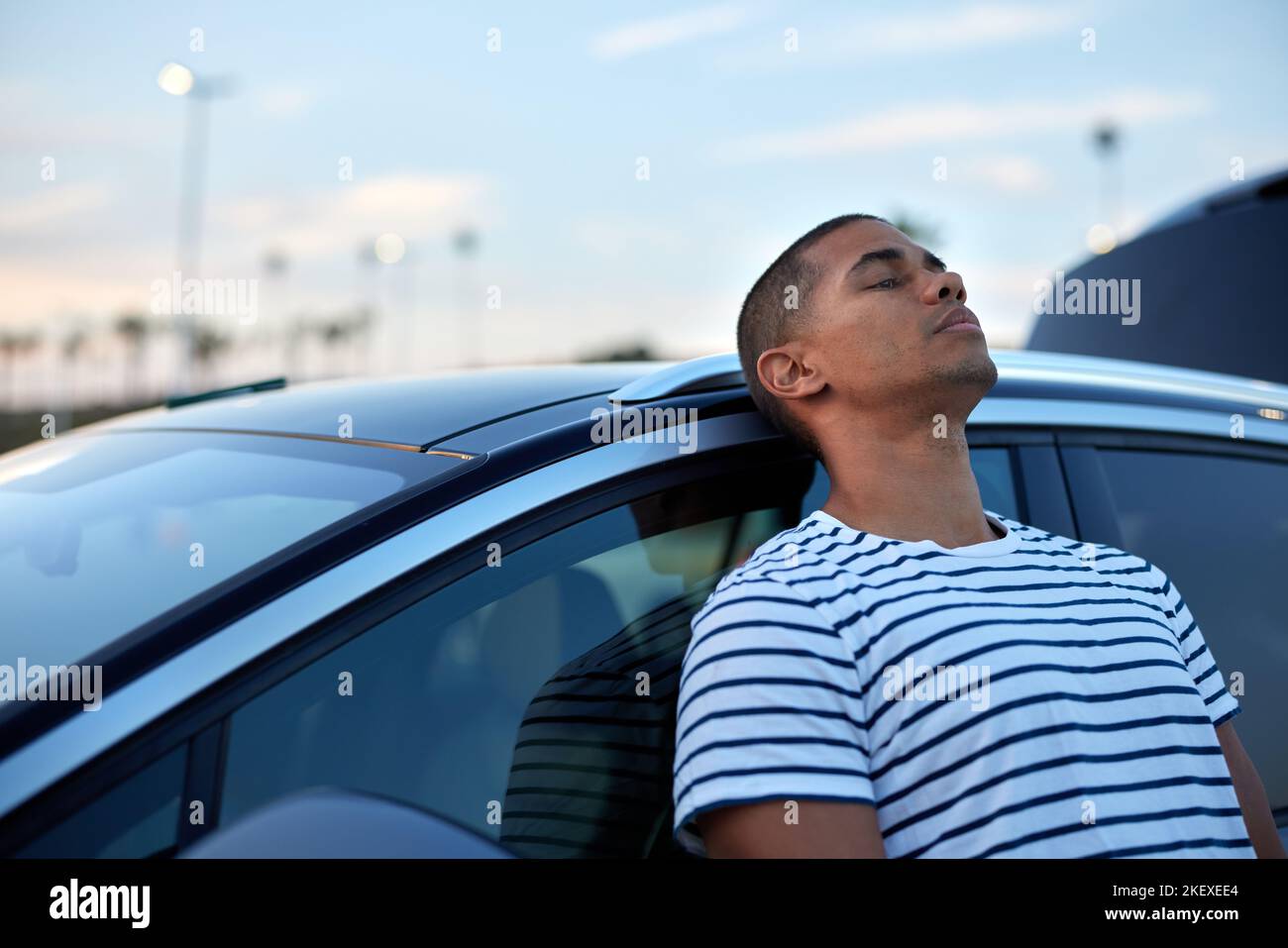 Tired man while leaning on car at sunset Stock Photo