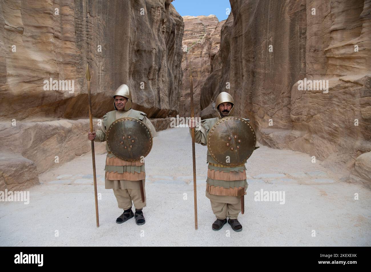 Two men dressed as Roman soldiers standing at beginning of siq or canyon for tourist photos Petra Jordan Stock Photo