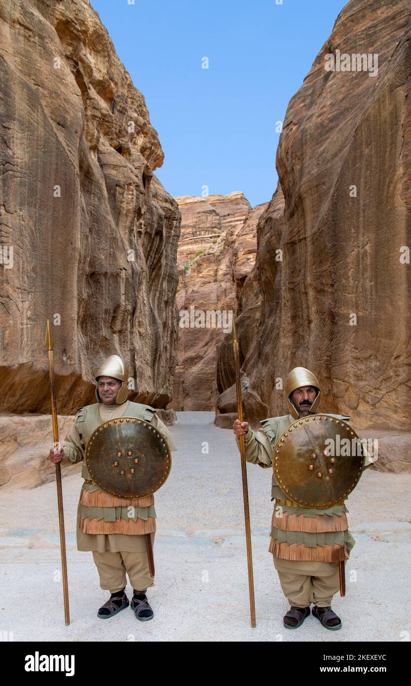 Two men dressed as Roman soldiers standing at beginning of siq or canyon for tourist photos Petra Jordan 1 Stock Photo