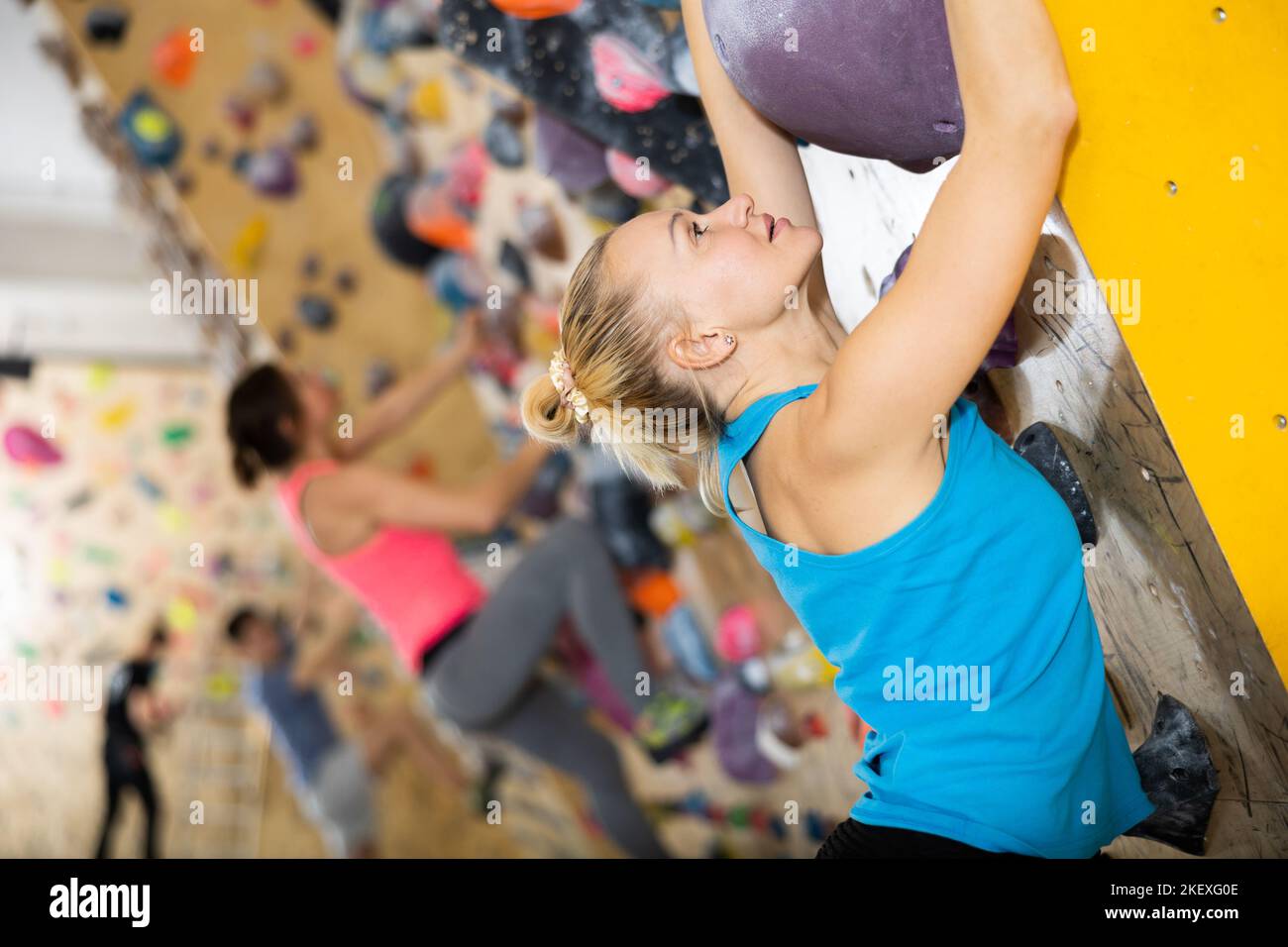 Positive woman training at bouldering gym without special climbing ...