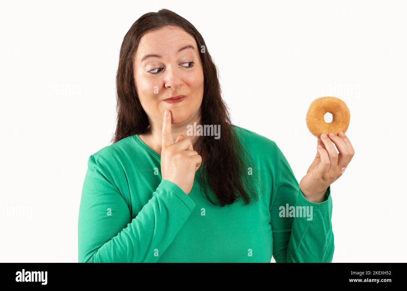 Adult woman over white grunge wall eating sugar donut serious face thinking about question, very confused idea Stock Photo