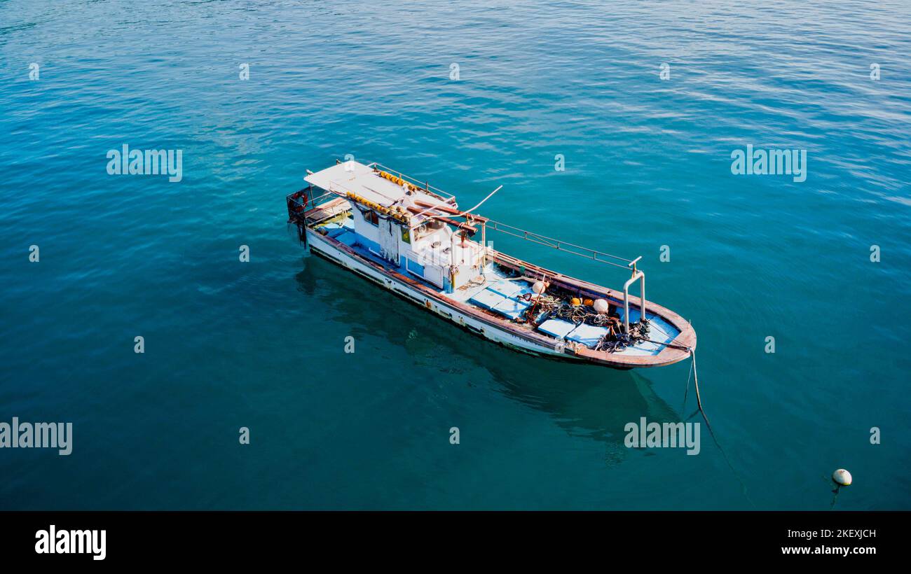 Fishing boat anchored behind coral reef Stock Photo