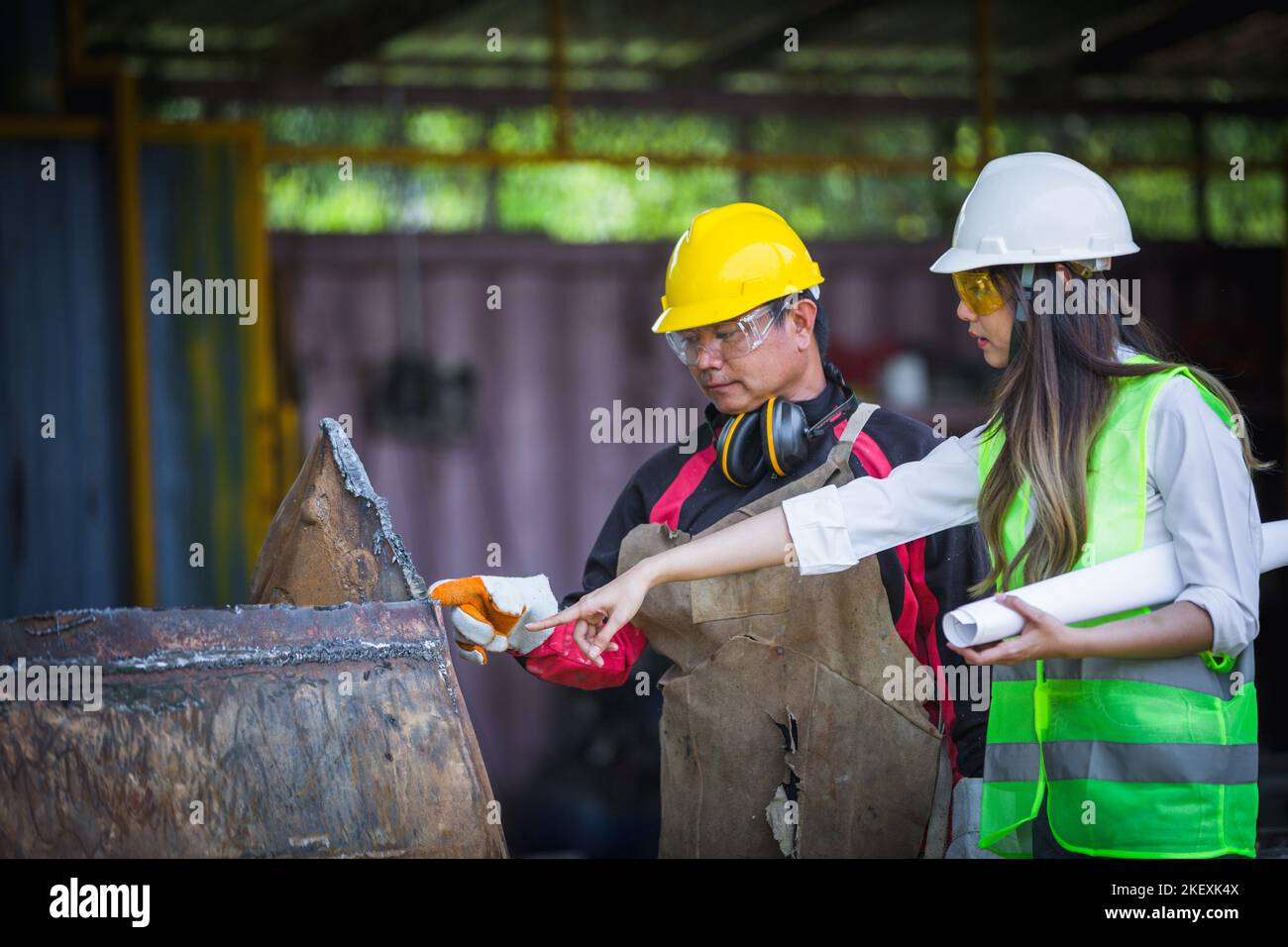 Asian female engineer checks workers' welds Stock Photo