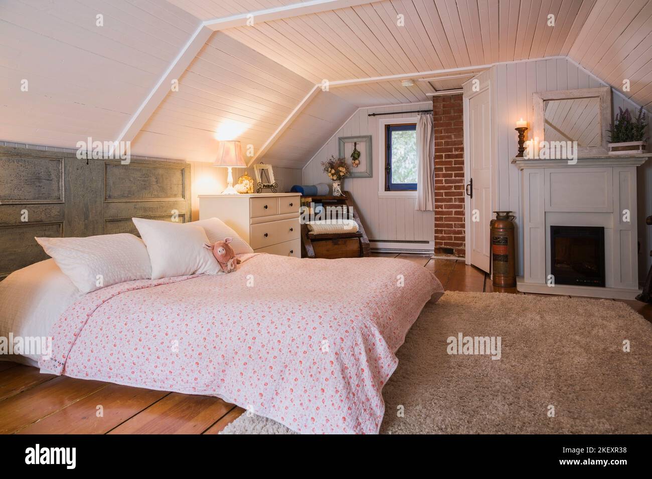 King size bed with salvaged door as a headboard and antique furniture in the master bedroom on the upstairs floor inside an old 1862 home. Stock Photo