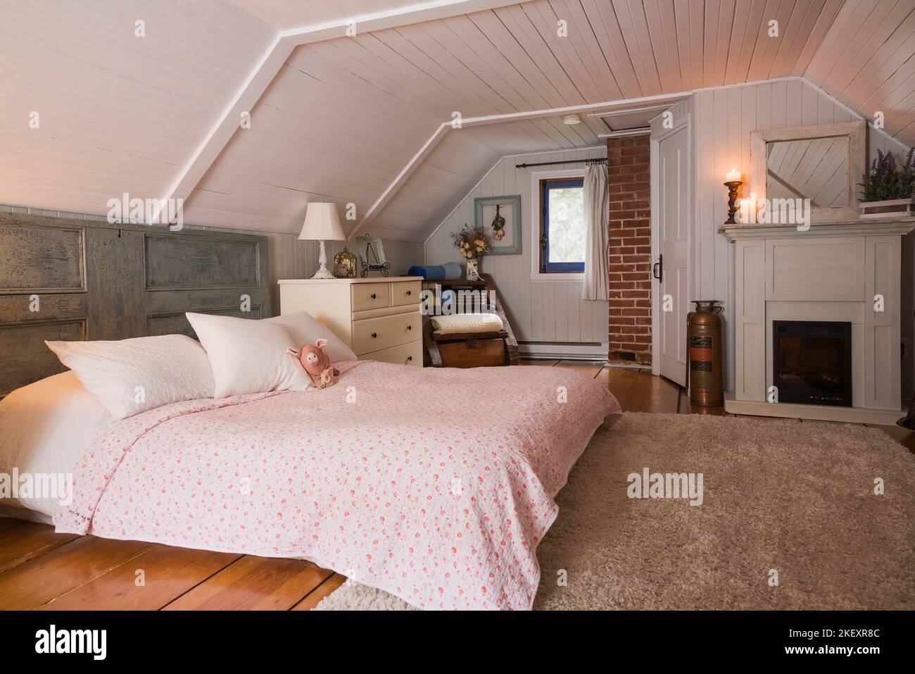 King size bed with salvaged door as a headboard and antique furniture in the master bedroom on the upstairs floor inside an old 1862 home. Stock Photo