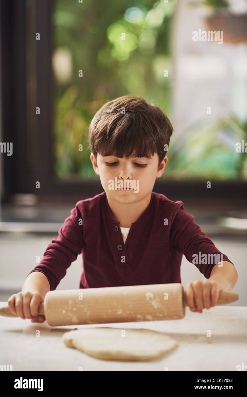 Hes a natural in the kitchen already. a young boy rolling dough in the kitchen. Stock Photo