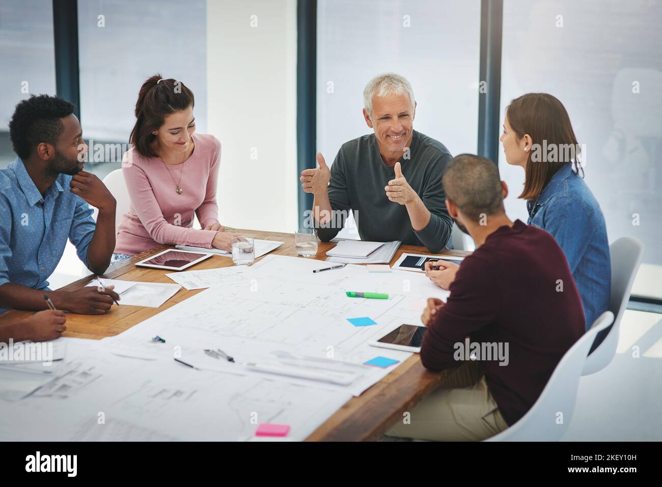 Blueprint Discussion Leading the creative discussion. a group of architects looking over ...