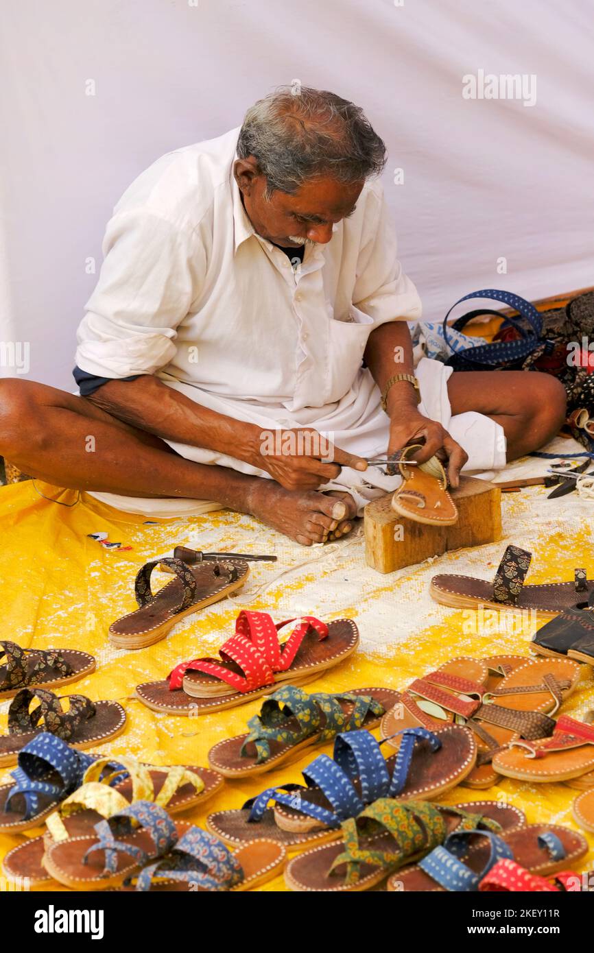 Pune, India - Nov 11 2022: A traditional shoe maker making a traditional colourful shoes and slippers in Local Market. Stock Photo
