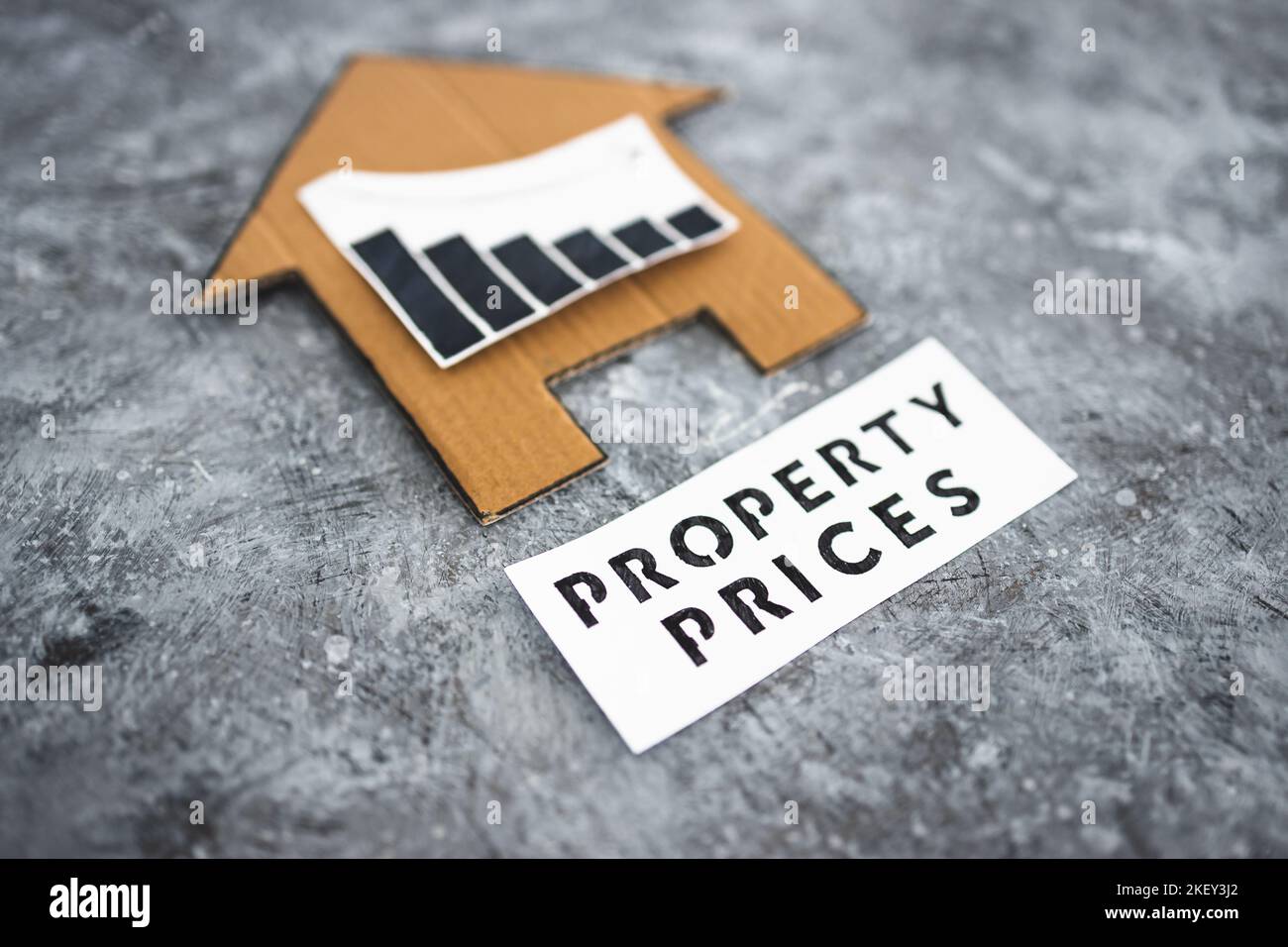 property prices dropping conceptual image, cardboard house with graphs ...