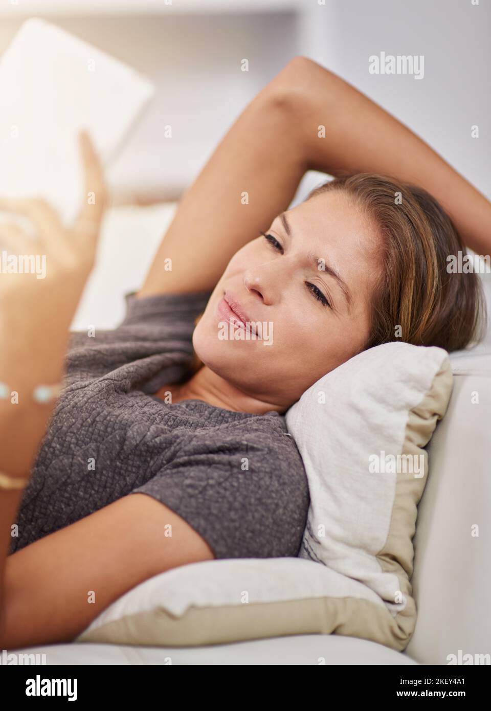 Curling up with a good e-book. a young woman relaxing on the sofa with a digital tablet at home. Stock Photo