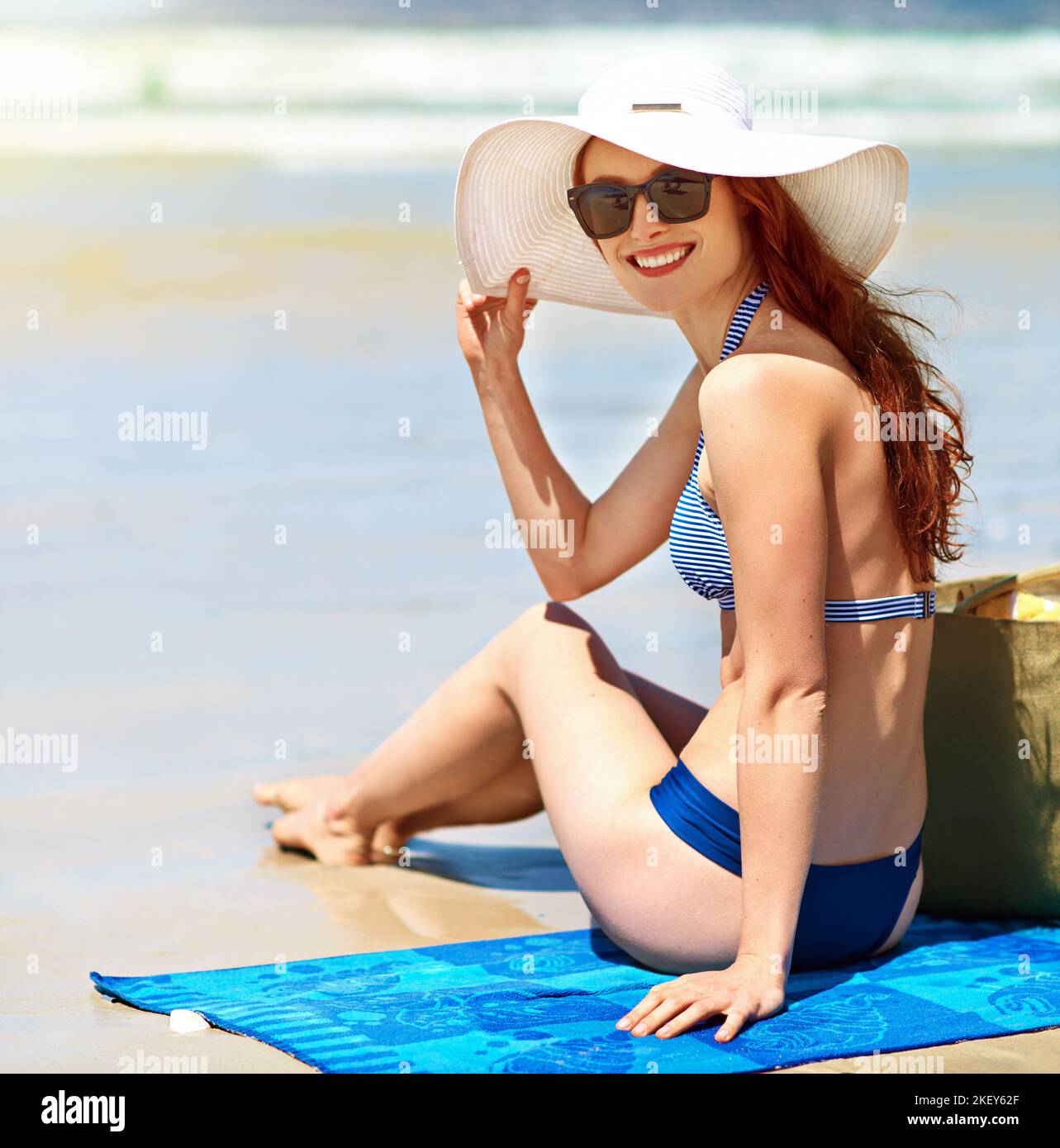 https://c8.alamy.com/comp/2KEY62F/have-a-seat-portrait-of-a-beautiful-young-woman-sitting-on-a-towel-at-the-beach-2KEY62F.jpg