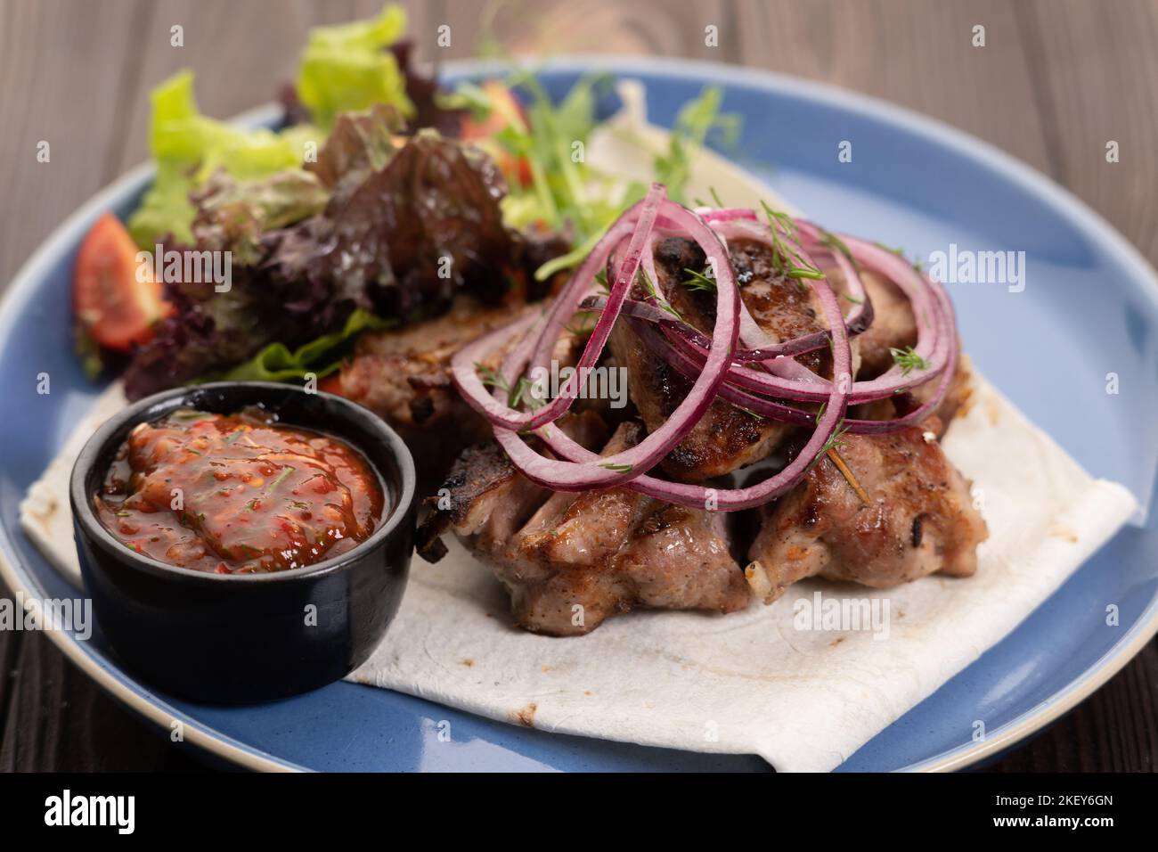 Healthy barbecue lean cubed pork kebabs served with a fresh lettuce, onion and tomato sauce, close up Stock Photo