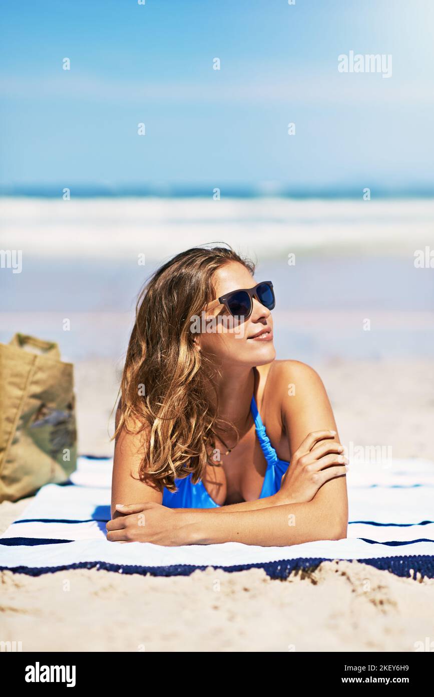 Spending some time in the sun. a beautiful young woman lying on a towel