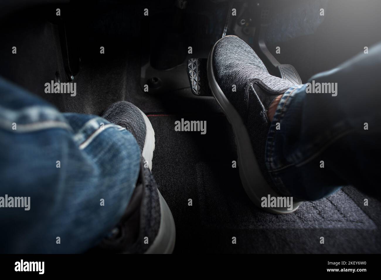 Close up the foot pressing brake pedal of a car. Driver stopping the