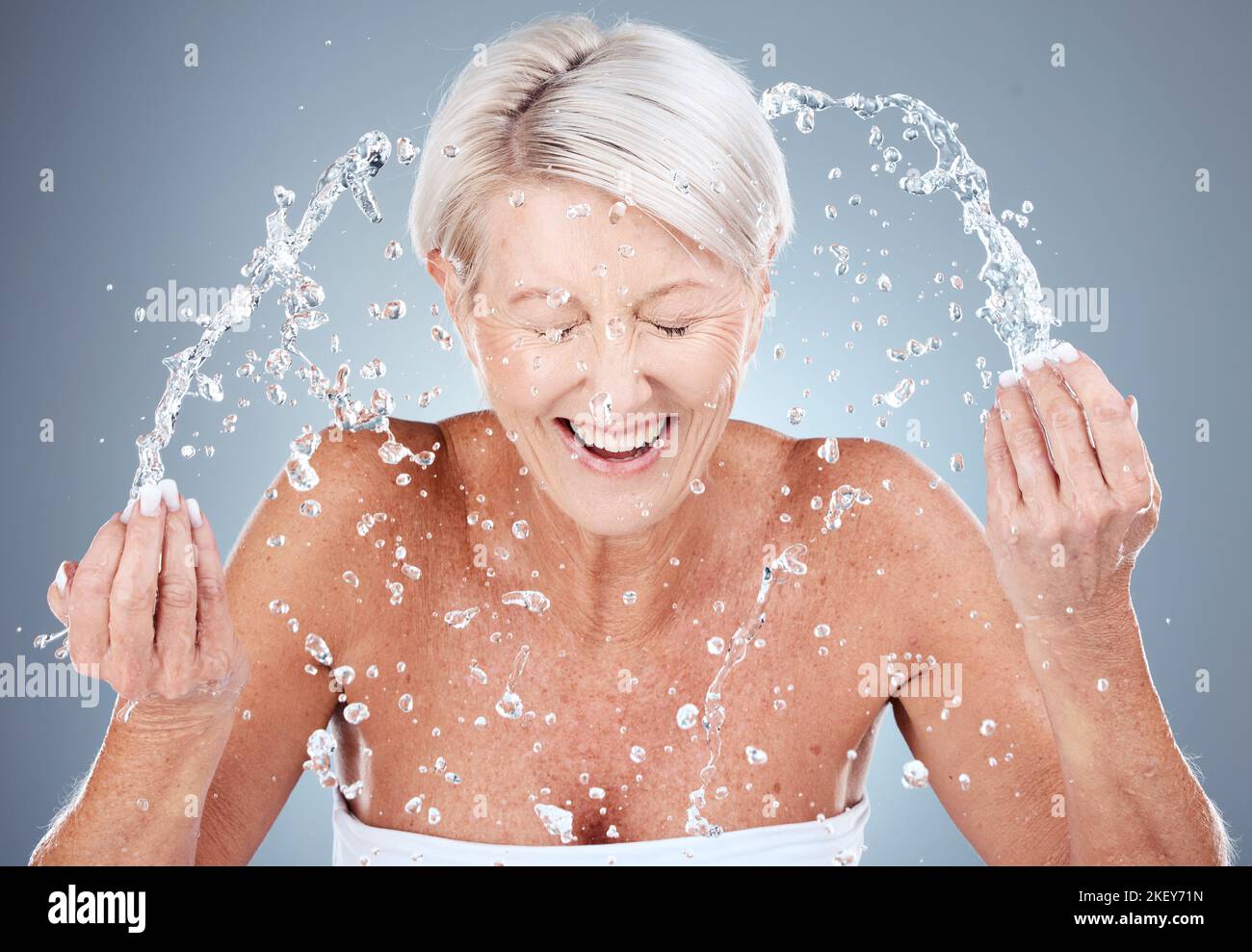 Mature woman, water splash or washing face in skincare grooming routine, morning hygiene maintenance or healthcare wellness. Smile, happy or elderly Stock Photo