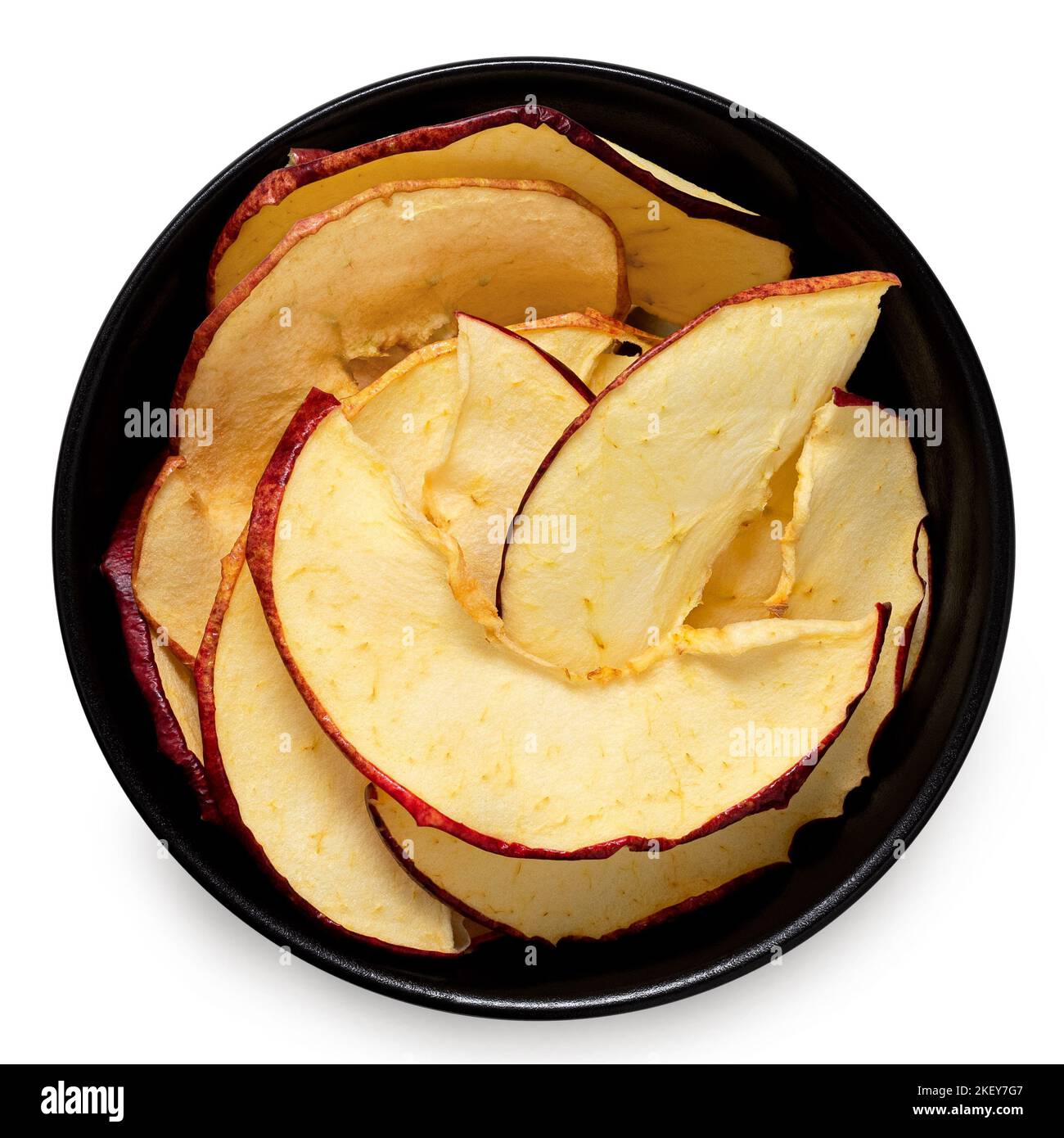 Dried apple slices in a black ceramic bowl isolated on white. Top view