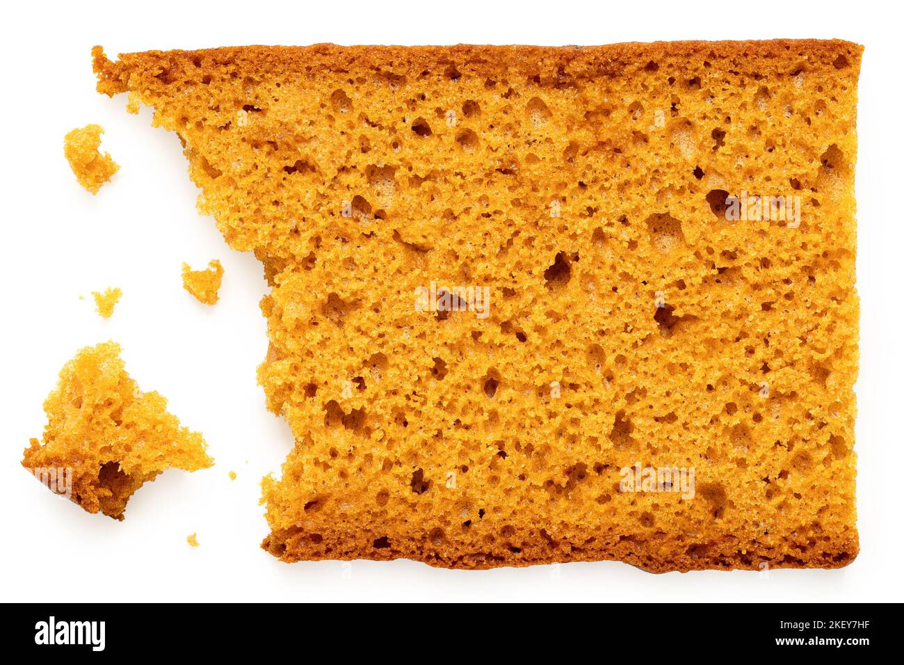 Partially eaten slice of spiced honey cake with crumbs isolated on white. Top view. Stock Photo