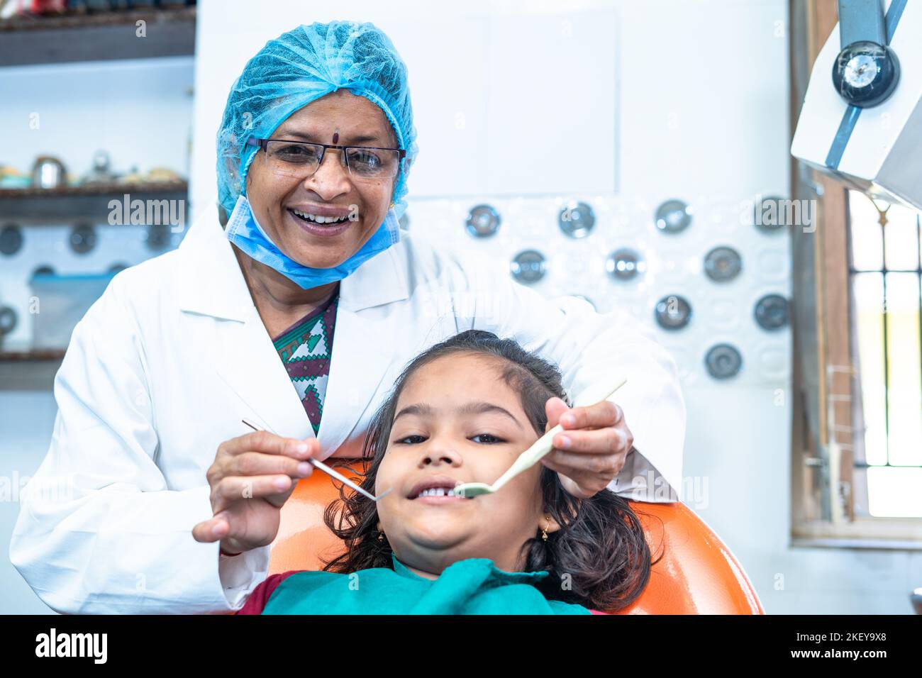 happy smiling dentist looking at camera while treating kid at hospital - concept of professional occupation, dental or oral care and treatment Stock Photo